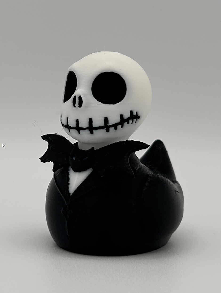 3D printed skeleton duck with skull head, hollow eyes, stitched grin, and black tuxedo with bat bow tie